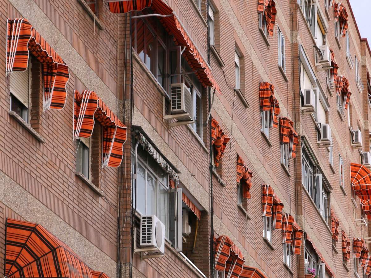 Bloque de viviendas de ladrillo con toldos naranjas, típico de los barrios residenciales de Madrid