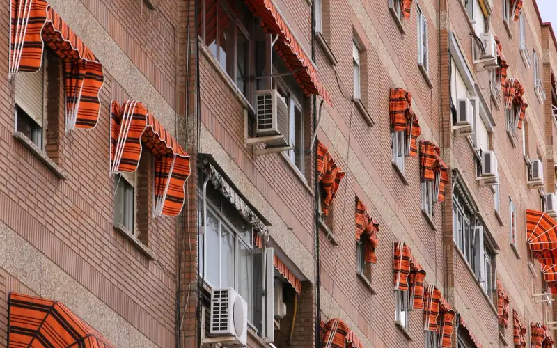 Fachada de ladrillo con ventanas y toldos en un bloque de viviendas