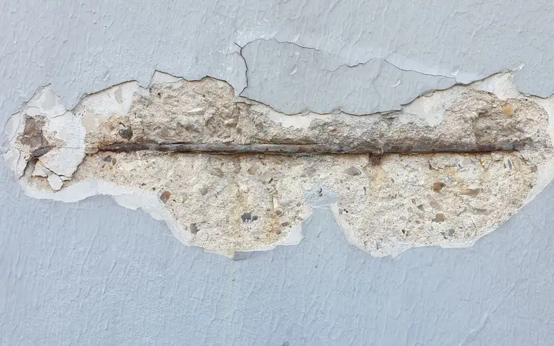 Detalle de un muro con el revestimiento desprendido y una armadura metálica a la vista