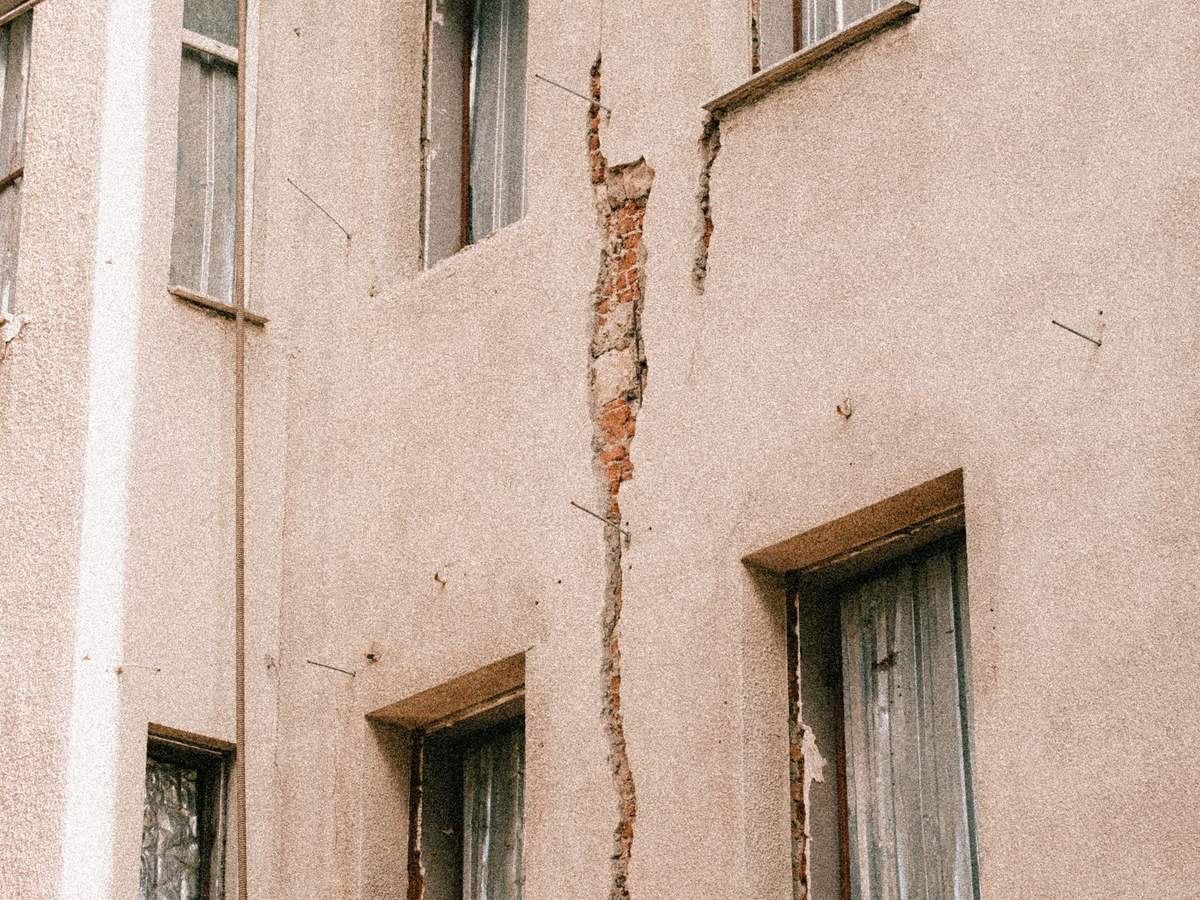 Fachada de un edificio con grietas en el revoco alrededor de las ventanas