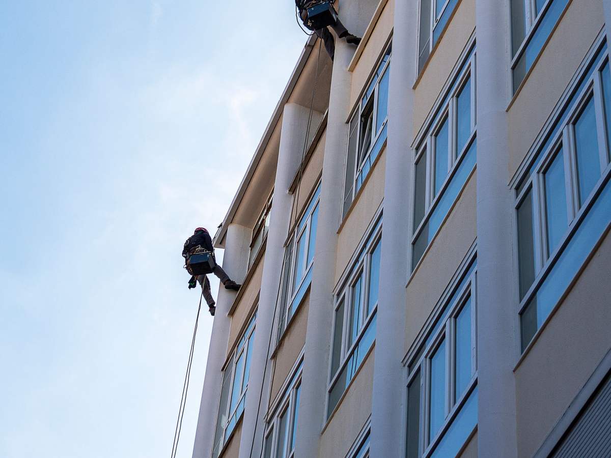 Limpiadores de cristales suspendidos con cuerdas en la fachada de un edificio de Madrid