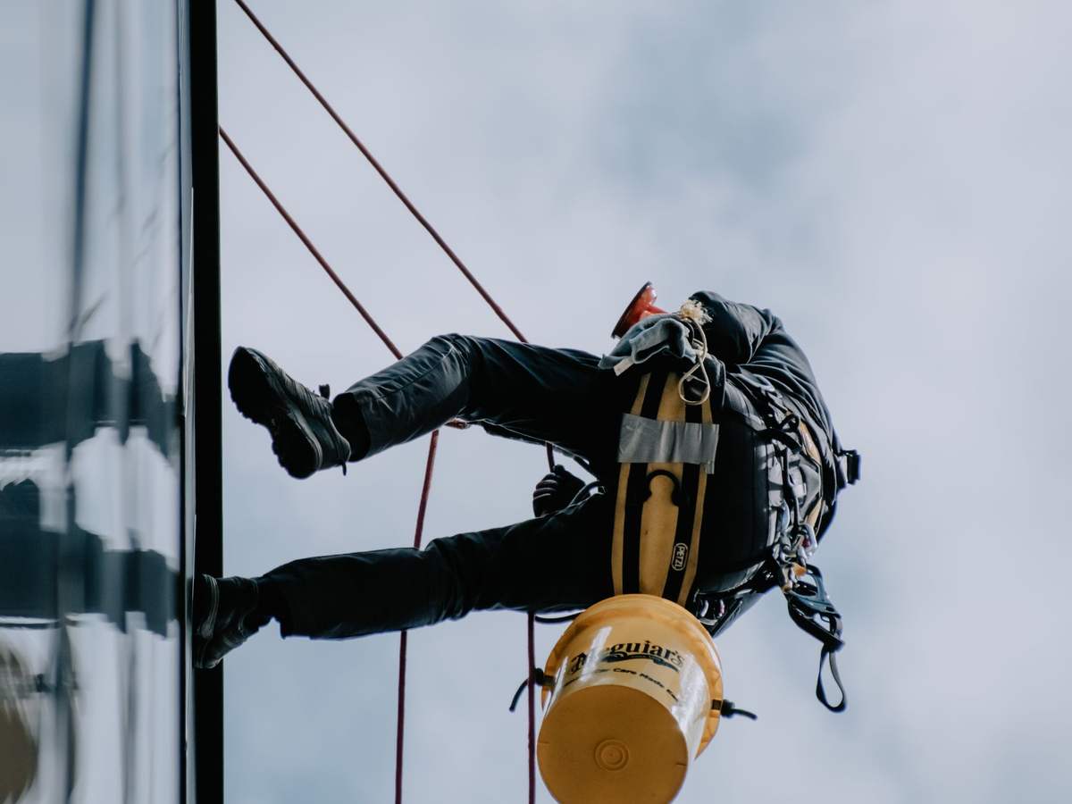 Técnico suspendido de una cuerda limpiando los cristales de un edificio